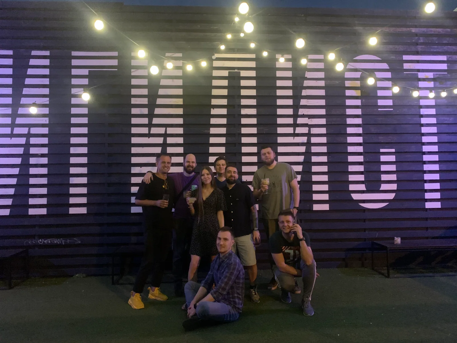 The team in front of a lettered wall at night